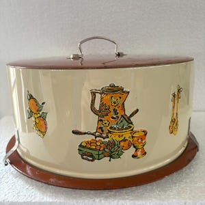 Vintage 1960s Cake Tin cream finished embossed cover having a brown lid and base, preowned and well used, the tin has spring holding clips.