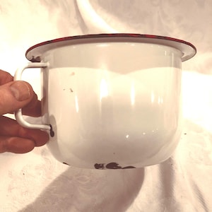 Un orinal antiguo de acero inoxidable esmaltado, un artículo típico de las granjas de las praderas canadienses, de segunda mano y con aspecto usado, de los años 30-40. Artículo decorativo.