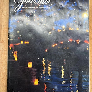 May include: A vintage issue of Gourmet magazine from December 1980. The cover features a nighttime scene with glowing lights reflected in water. The magazine title is in elegant script, with the tagline "The Magazine of Good Living."
