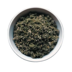 May include: A white bowl filled with dried green herbs. The herbs are a mix of different types, including leaves and stems.