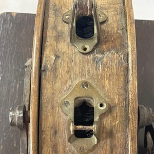 May include: Close-up of a weathered wooden barrel with brass hardware. The barrel features two brass clasps and a keyhole, showcasing an antique aesthetic. The wood has visible grain and signs of age.