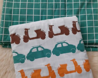 May include: A white fabric with a pattern of brown, orange, and green scooters and cars. The fabric is folded in half and has a green and white checkered fabric behind it.