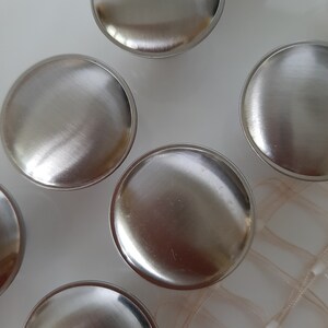 K&ouml;nnte beinhalten: F&uuml;nf runde silberne Schrankkn&ouml;pfe mit geb&uuml;rsteter Oberfl&auml;che.