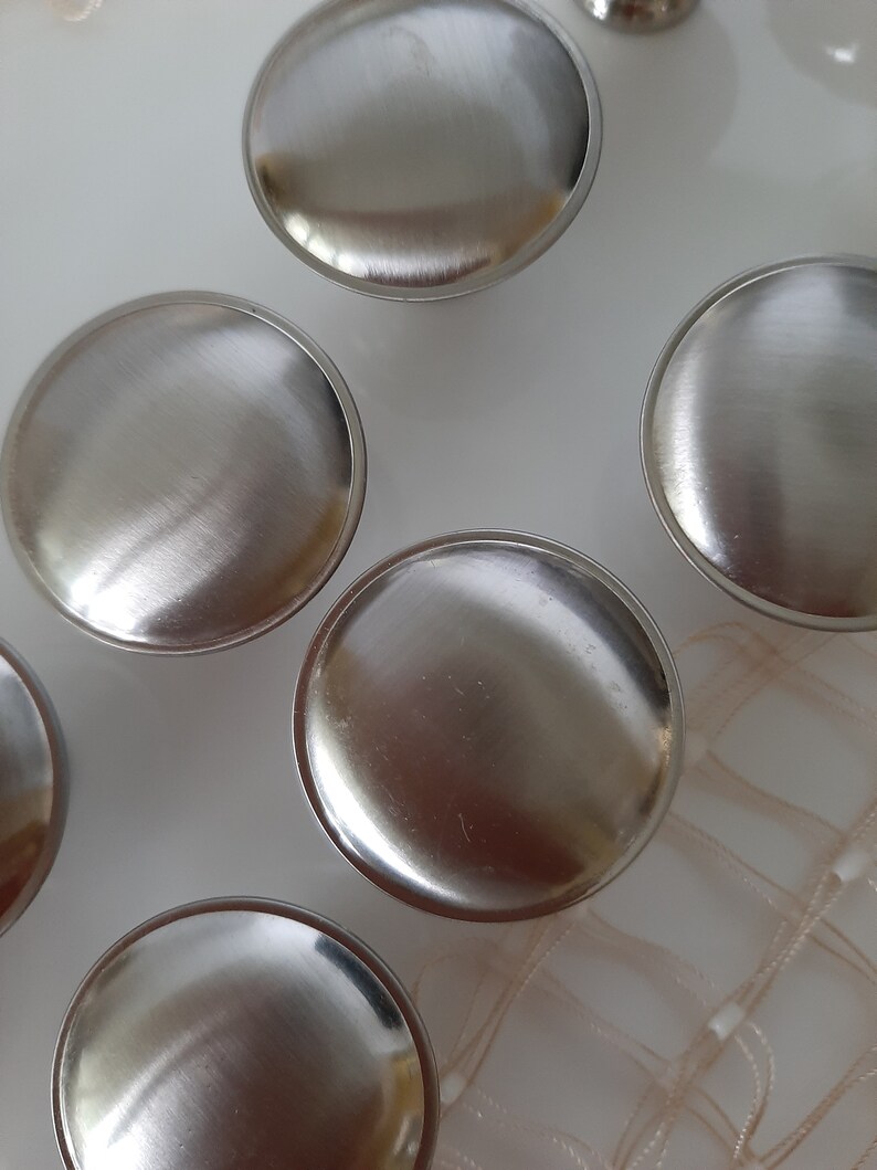 K&ouml;nnte beinhalten: F&uuml;nf runde silberne Schrankkn&ouml;pfe mit geb&uuml;rsteter Oberfl&auml;che.