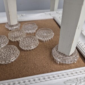 Può includere: Un set di sottobicchieri circolari e trasparenti per gambe di mobili, dotati di una base inferiore testurizzata con punte per una maggiore aderenza. Questi dischi in plastica sono progettati per essere posizionati sotto le gambe bianche.