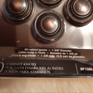 Może przedstawiać: Opakowanie 10 gałek meblowych z brązu olejowanego. Gałki są okrągłe i mają średnicę 3,5 cm. Opakowanie zawiera r&oacute;wnież tekst "CABINET KNOBS, POIGNEES D'ARMOIRE RONDES, POMOS PARA ARMARIOS, BP1586-0RB".