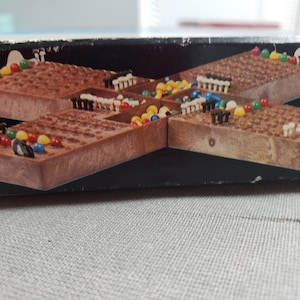 Peut inclure: Un plateau de jeu en bois avec un motif en grille et des billes colorées. Le plateau est divisé en quatre sections, chacune avec une couleur de bille différente. Le plateau est en bois et a une finition brune.