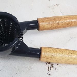 May include: A blue and wood nutcracker with a spring mechanism. The nutcracker has two wooden handles.