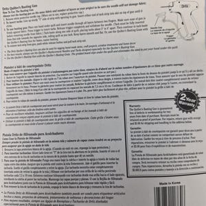 May include: A Dritz Quilter's Basting Gun packaging card featuring detailed instructions in English, French, and Spanish. The card includes a diagram of the tool, a 2-year warranty seal, a barcode, and manufacturing information printed on white paper.