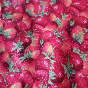 Puede incluir: Primer plano de una tela con un patrón repetido de fresas rojas maduras con hojas verdes. El diseño crea una sensación vibrante y veraniega. La tela parece ser de algodón, ideal para diversos proyectos.