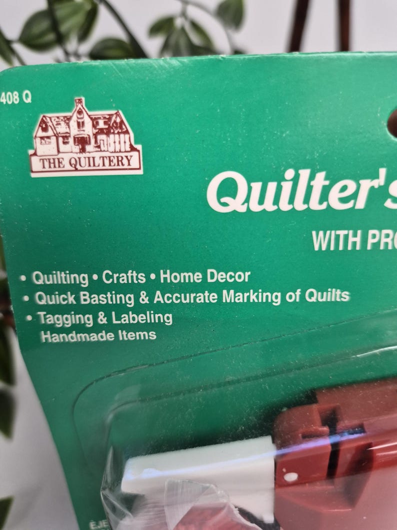 May include: A green product packaging card for The Quiltery Quilter's tool. The text lists uses including quilting, crafts, home decor, quick basting, accurate marking of quilts, and tagging and labelling handmade items. The card is partially visible.