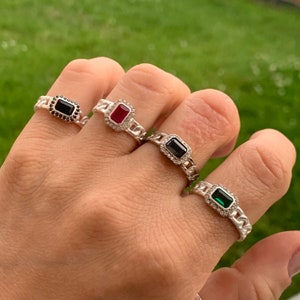 May include: Four silver rings with different coloured gemstones. The rings feature a chain link design and each stone is surrounded by smaller clear stones.