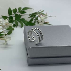 May include: A silver ring with a triple band design. The bands are textured with small beads and the ring is open ended.