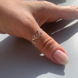 May include: A silver thumb ring featuring a delicate leaf design. The ring is open and adjustable to fit most thumb sizes.