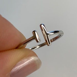 Op de afbeelding: Een zilveren ring met een eenvoudig ontwerp met twee verticale balken. De ring is gemaakt van metaal en heeft een gepolijste afwerking.