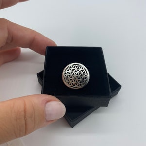 Op de afbeelding: Een zilveren ring met een levensbloemontwerp in een zwarte ringdoos.