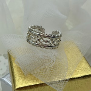 Può includere: Un anello in filigrana d'argento con un design delicato. L'anello è aperto e regolabile per adattarsi alla maggior parte delle dimensioni delle dita.