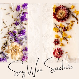 May include: Two white soy wax sachets with dried flowers. The sachet on the left has purple flowers and the sachet on the right has yellow and red flowers. The text "Soy Wax Sachets" is written below the sachets.