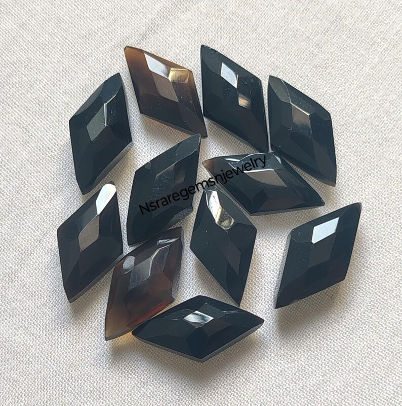 May include: A collection of twelve black and brown diamond-shaped gemstone cabochons. The cabochons are faceted and have a polished finish.