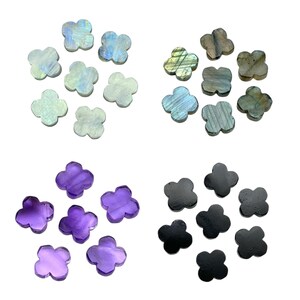 May include: A collection of gemstone clover shapes in various colors. The gemstones include iridescent white, blue-green, gray-green, purple, and black. The clover shapes are arranged in groups on a white background.