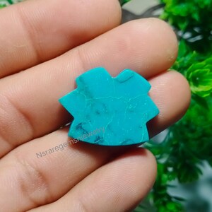 May include: A turquoise gemstone with a unique, star-shaped design. The stone has a smooth, polished surface and a vibrant blue color.