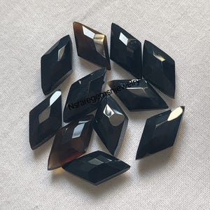 May include: Ten black and brown faceted gemstone cabochons in a diamond shape.