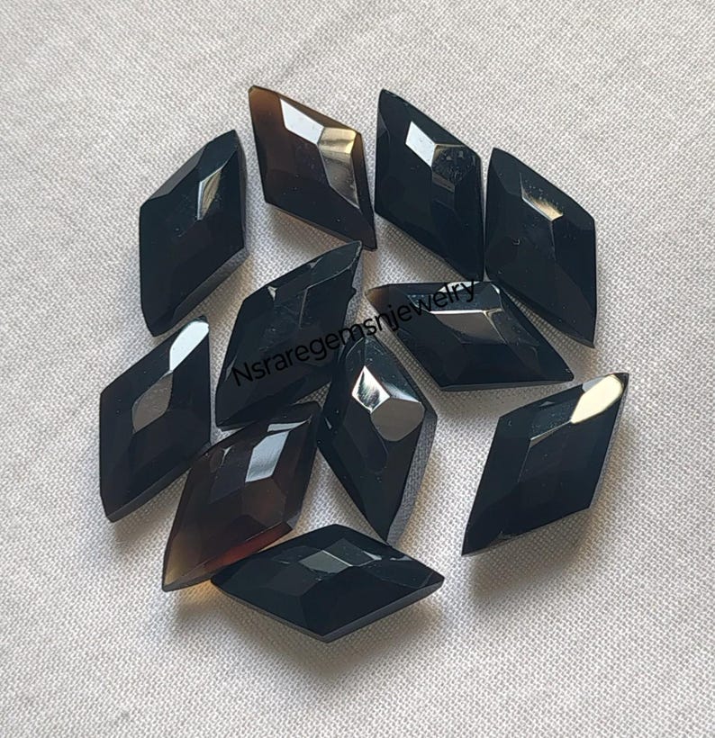 May include: Ten black and brown faceted gemstone cabochons in a diamond shape.