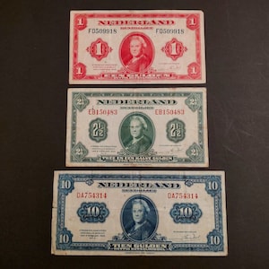 May include: Three vintage Dutch banknotes, one red, one green, and one blue, with the denomination printed in the centre. The red banknote is for 1 guilder, the green banknote is for 2 1/2 guilders, and the blue banknote is for 10 guilders.
