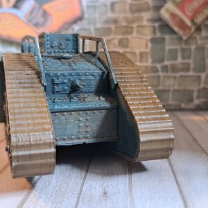 Op de afbeelding: Een blauw en bruin model van een tank uit de Eerste Wereldoorlog met rupsbanden. De tank is gemaakt van plastic en heeft een gedetailleerd ontwerp.
