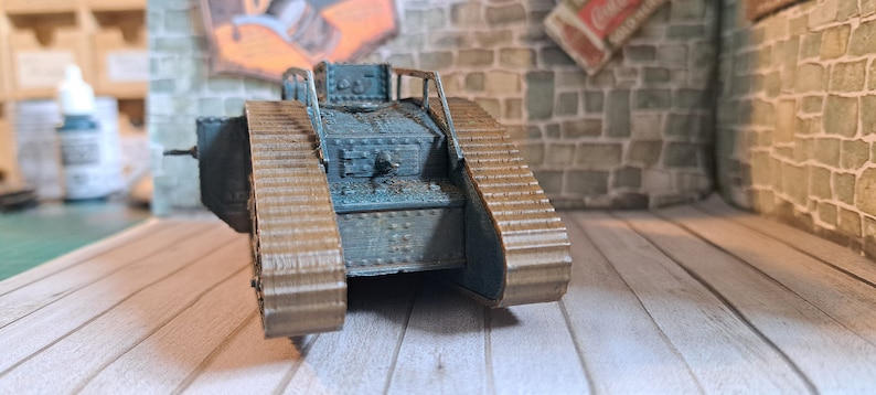 Op de afbeelding: Een blauw en bruin model van een tank uit de Eerste Wereldoorlog met rupsbanden. De tank is gemaakt van plastic en heeft een gedetailleerd ontwerp.