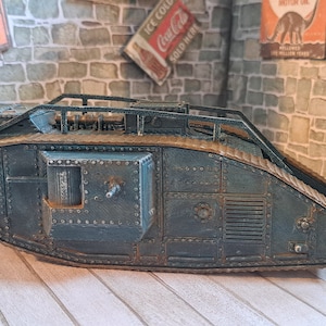 Op de afbeelding: Een gedetailleerd model van een tank uit de Eerste Wereldoorlog, geschilderd in donkergroen met roestkleurige accenten. De tank is gemaakt van metaal en heeft een realistisch ontwerp.