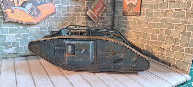 Op de afbeelding: Een gedetailleerd model van een tank uit de Eerste Wereldoorlog, geschilderd in donkergroen met roestkleurige accenten. De tank is gemaakt van metaal en heeft een realistisch ontwerp.