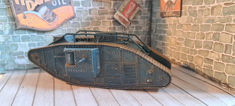 Op de afbeelding: Een donkergroen model van een tank uit de Eerste Wereldoorlog met een bruin rupsband en een gedetailleerd ontwerp. De tank is gemaakt van metaal en heeft een realistische uitstraling.
