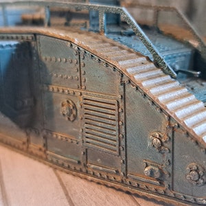 Op de afbeelding: Een close-up van een model van een tank uit de Eerste Wereldoorlog, geschilderd in donkergroen met roestkleurige accenten. De tank heeft een gedetailleerd ontwerp met zichtbare rupsbanden en een grote geschutskoepel.