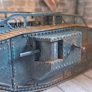 Op de afbeelding: Een gedetailleerd model van een tank uit de Eerste Wereldoorlog, geverfd in een donker teal kleur. De tank heeft een verhoogd, open dak en een groot, rechthoekig luik aan de achterkant. Het model is gemaakt van plastic en heeft een realistische, verweerde uitstraling.