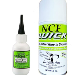 May include: Two bottles of Satellite City instant glue. The smaller bottle is labeled "Special T" and is 2 ounces. The larger bottle is labeled "NCF Quick" and is 6 ounces. Both bottles are white with green and black accents.