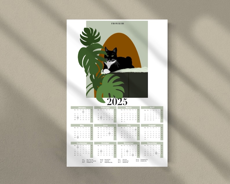 May include: A 2025 calendar featuring a black and white cat lounging on a brown and green surface. The cat is surrounded by green tropical leaves. The calendar is divided into 12 months, with each month displayed in a separate box.