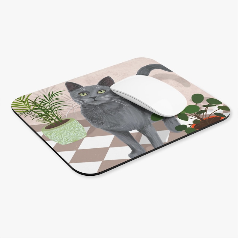 May include: A grey cat with green eyes stands on a chequered floor with two potted plants. A white computer mouse is on the floor next to the cat. The mouse pad is a light brown colour with a pink background.