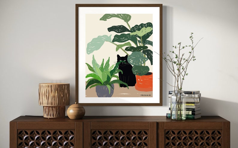 May include: A framed illustration of a black cat sitting in a pot of green plants. The cat is looking directly at the viewer. The background is a light beige color. The text "Studio No. 8" is in the bottom right corner of the image.