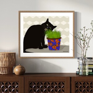 Peut inclure: Un chat noir aux yeux verts mange de l'herbe dans un pot &agrave; motifs bleus et orange. Le chat est assis sur une surface brun clair avec un motif g&eacute;om&eacute;trique gris clair et blanc en arri&egrave;re-plan.