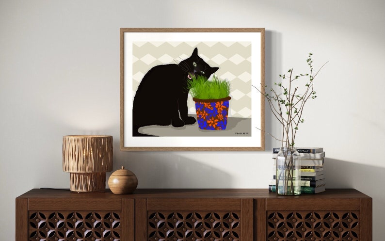 Peut inclure: Un chat noir aux yeux verts mange de l'herbe dans un pot &agrave; motifs bleus et orange. Le chat est assis sur une surface brun clair avec un motif g&eacute;om&eacute;trique gris clair et blanc en arri&egrave;re-plan.