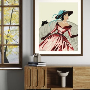 May include: A framed illustration of a woman wearing a red and pink dress and a large hat with a blue ribbon. She is sitting on a couch with a black cat beside her. The text "From Ruru" is at the bottom of the illustration.