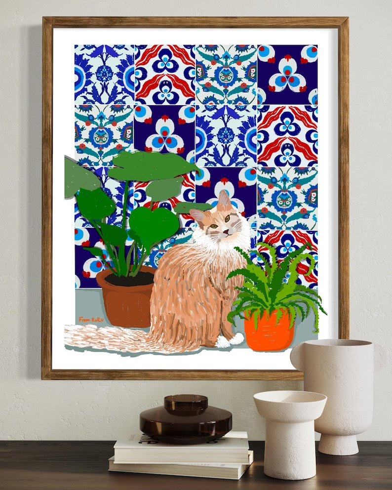 May include: A framed illustration of a ginger cat sitting in front of a wall with blue and white patterned tiles. The cat is surrounded by two potted plants, one with green leaves and the other with a fern. The illustration is signed "From Lulu".