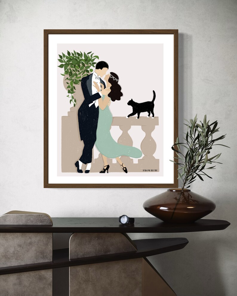 May include: A framed illustration of a couple dancing on a balcony with a black cat watching them. The illustration is in a minimalist style with muted colors and a simple background. The text "FROM BLUE" is at the bottom of the illustration.