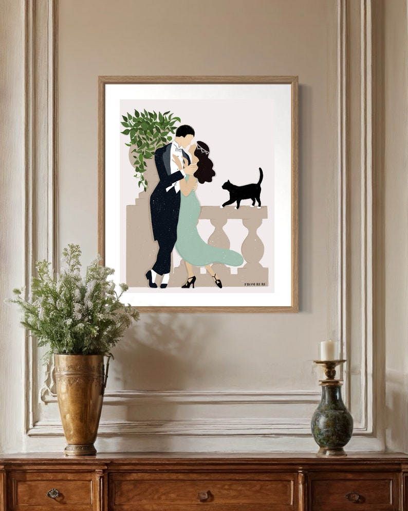 May include: A framed illustration of a couple dancing on a balcony with a black cat watching them. The man is wearing a tuxedo and the woman is wearing a green dress. The illustration is set against a light brown background.