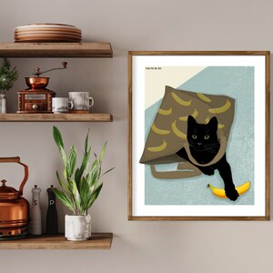 K&ouml;nnte beinhalten: Eine schwarze Katze mit gr&uuml;nen Augen sitzt in einer braunen Tasche mit Bananenmuster. Die Katze h&auml;lt eine gelbe Banane in ihrer Pfote. Die Tasche befindet sich auf einem hellblauen Hintergrund. Das Bild tr&auml;gt den Titel "From Me To You".