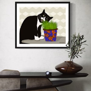 Peut inclure: Un chat noir et blanc aux yeux verts mange de l'herbe dans un pot bleu et orange &agrave; motifs floraux. Le chat est assis sur un fond beige &agrave; motif chevron. Le texte "FROM OUR BE" est visible dans le coin inf&eacute;rieur droit de l'image.