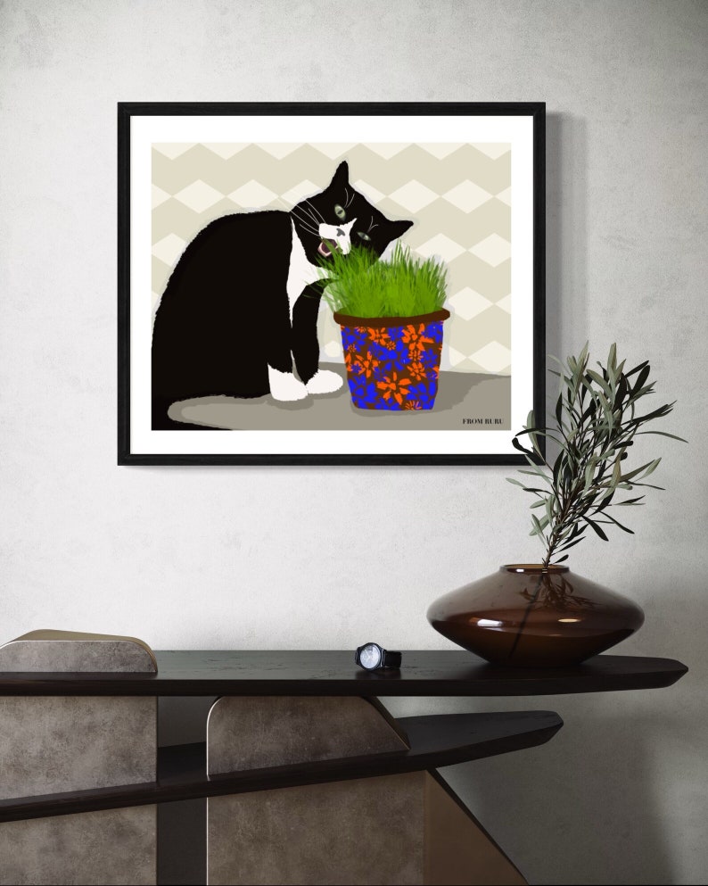 Peut inclure: Un chat noir et blanc aux yeux verts mange de l'herbe dans un pot bleu et orange &agrave; motifs floraux. Le chat est assis sur un fond beige &agrave; motif chevron. Le texte "FROM OUR BE" est visible dans le coin inf&eacute;rieur droit de l'image.