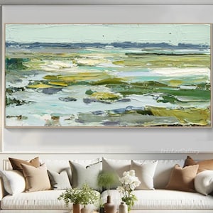 Könnte beinhalten: Abstrakte Landschaftsmalerei mit einem strukturierten Impasto-Stil. Das Kunstwerk zeigt eine Palette aus Grün-, Blau- und Gelbtönen, die eine Marsch- oder Küstenlandschaft darstellen. Das Gemälde ist in einem goldfarbenen Rahmen gerahmt und hängt über einem weißen Sofa.