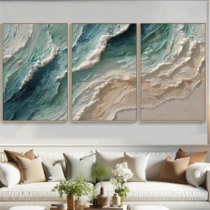 Puede incluir: Tres obras de arte enmarcadas que representan una escena oceánica abstracta. La obra presenta olas texturizadas en tonos turquesa, blanco y beige, creando una sensación de profundidad y movimiento. Los marcos son de color dorado claro.